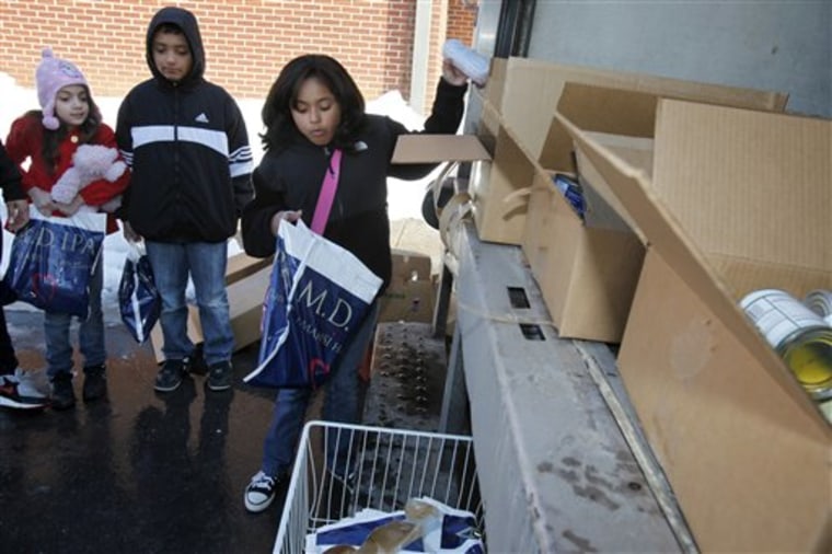 In this Friday Jan. 12, 2010 photo, Jennifer Rivera, 7, Peter Luque, 10, and Ruth Pereira, 9, left to right, choose cans of food being provided to families whose children are usually in the school lunch program at Rolling Terrace Elementary School in Takoma Park, Md., in the aftermath of back-to-back blizzards. (AP Photo/Jacquelyn Martin)